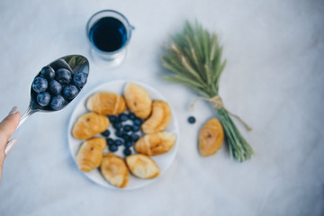 Fototapeta na wymiar healthy light breakfast. blue tea from orchids, blueberries on a spoon, croissant on a plate with spikelets of wheat. top view proper nutrition for a slim figure. raw food vegetarianism. diet