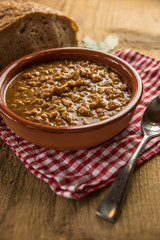 tripe stew sauce in brown ceramic pot on a wood table 
