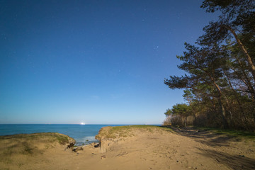 View from the edge of a small sandy cliff to the Baltic seashore late at night