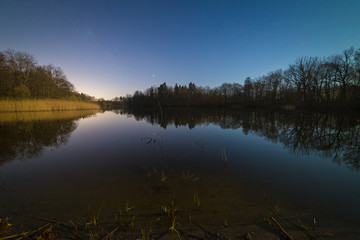 Fototapeta na wymiar Calm forest lake late at starry night