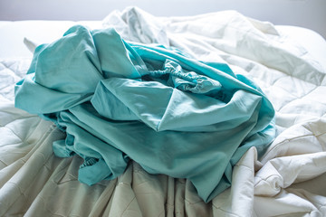 Turquoise and White crumpled bed sheet on white bed, Close up shot, Selective focus, Bedroom cleaning concept