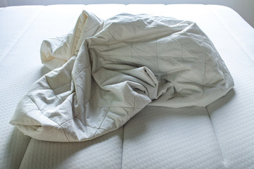 White crumpled bed sheet on white bed, Close up shot, Selective focus, Bedroom cleaning concept