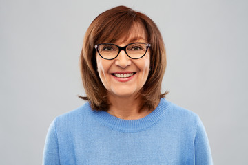 vision and old people concept - portrait of smiling senior woman in glasses over grey background