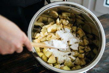 Woman making apple pie and adding spice