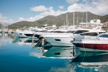 Fototapeta premium Many yachts moored at the coast in Porto Montenegro in Tivat in Montenegro against the backdrop of a beautiful mountain landscape. Summer sea vacation