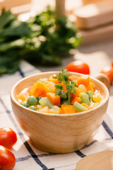 Ladle of steamed freshly harvested young vegetables including crinkle cut sliced carrots, peas and potato for a healthy accompaniment to dinner