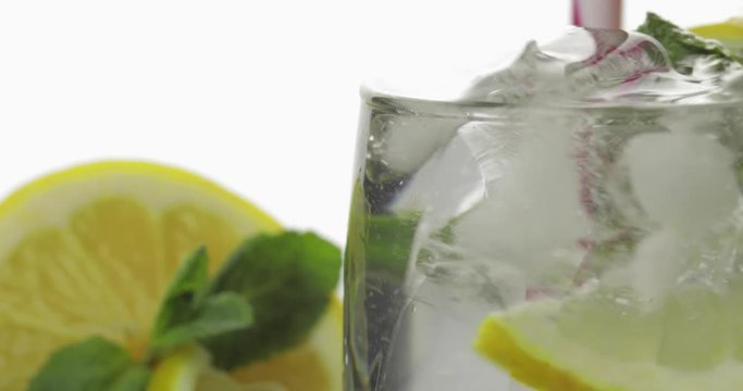 Stiring in a glass with cold drink, leaves of mint, lime, lemon and ice cubes
