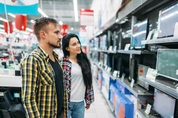 Young couple buying monitor in supermarket