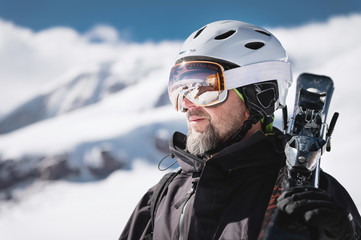 Close-up Portrait bearded male skier aged against background of snow-capped Caucasus mountains. Ski resort concept