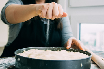 Woman sprinkling apple pie with sugar