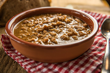 tripe stew sauce in brown ceramic pot on a wood table 