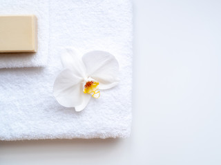 Obraz na płótnie Canvas Wellnessbehandlung, Weißes Handtuch mit Seife und Orchideeblüte