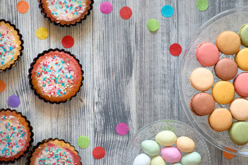Easter flat lay with macarons, muffins and marzipan eggs jn a decorative tray on textured grey wood