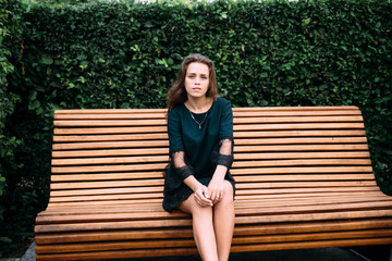 Beautiful young girl in a green dress on a bench