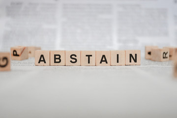 Abstain Word Written In Wooden Cube - Newspaper