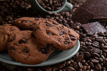 coffee beans with chocolate and cookies in a cup and a plate