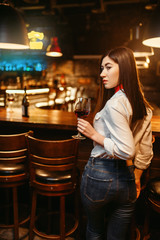 Woman with glass of red wine at wooden bar counter