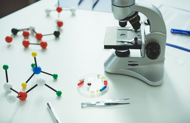 Modern microscope and plate with medicine standing in laboratory