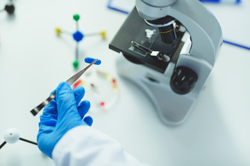 Scientist holding capsule with tweezers in laboratory