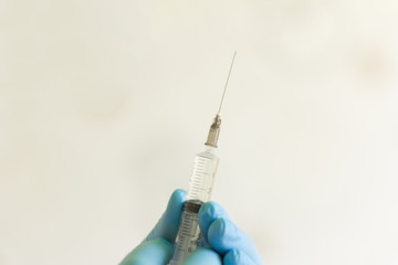 doctor's hand in gloves holding a syringe with medication for injection
