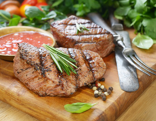 grilled beef steak on a cutting board with spices .