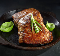 Grilled beef steak in a pan with spices.