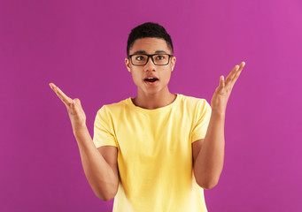Portrait of shocked African-American teenage boy on color background