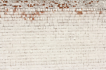 white brick wall of an old building with fallen off paint