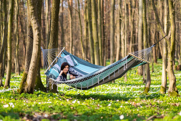 Happy healthy eating girl drinking green smoothie detox outdoors in hammock. Woman on weight loss diet vegan nutrition cleanse.