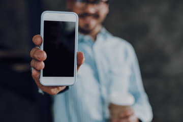 Young man with drink is showing smartphone screen