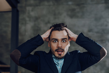 Astonished young man in trendy clothes inside