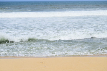 Fototapeta na wymiar waves on the beach with beautiful white sand and blue sky background