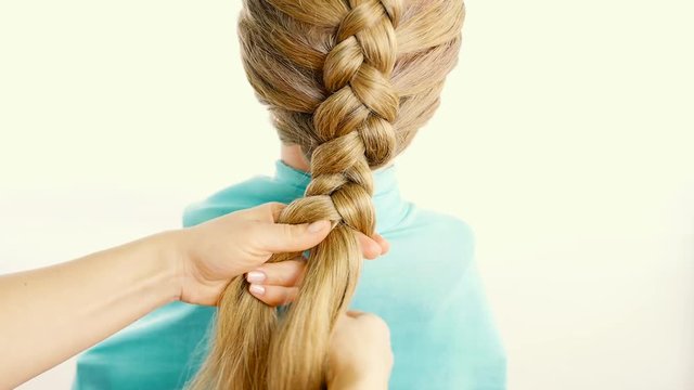Girl braids a braid on a training pig. Weave classic braid