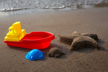 Fototapeta na wymiar Children's toys for sand and starfish made from sand. Sandy beach, sunny day.