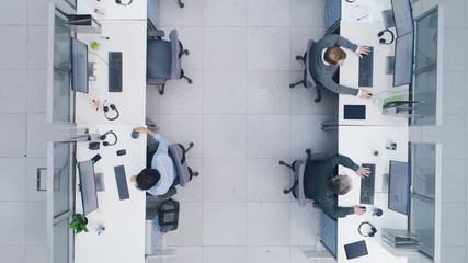 Aerial Top Down Drone Shot of Big Busy Corporate Office with Tow Rows off Businessmen and Businesswomen Working on Desktop Computers. Bright Open Space Office with Businesspeople and Salespeople