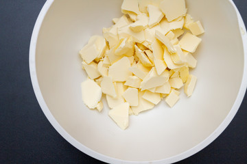 Pieces of butter are in a bowl for mixing in the preparation of cookies
