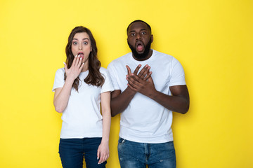 Surprised interracial couple with big eyes looking at camera in studio