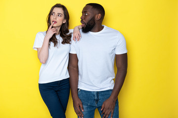 Obraz premium Young interracial couple in white T-shirts posing for camera in studio