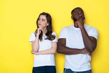 Young interracial couple in white T-shirts posing for camera in studio