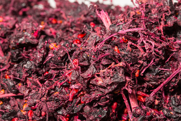 Macro view of dried red grape scraps, showing the stalks and dried fruit.