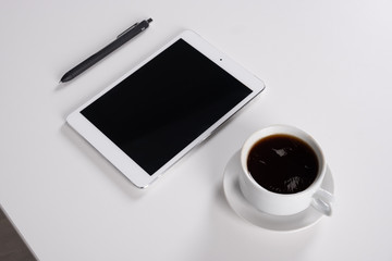 Fototapeta na wymiar digital tablet and coffee cup on wite table