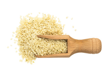 Shelled or peeled hemp seeds on a wooden spoon or scoop with pile next to it seen directly from above and isolated on white background