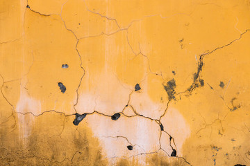 Vintage cracked wall texture. Yellow painted and distressed surface. Grunge background