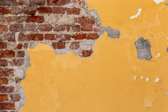 Vintage yellow wall texture with red bricks. Cracked paint on grunge background.