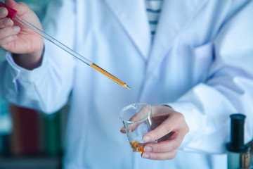  Close up scientist hand pouring orange liquid