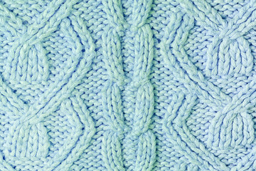 Knitted texture with patterns close-up. Blank blue background for layouts. Light photo.