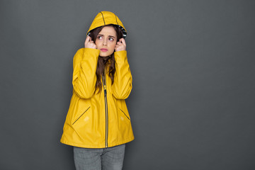 Cropped photo of frustrated Caucasian girl dressed in yellow raincoat in studio