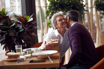 Elegant woman gratefully kissing man for present