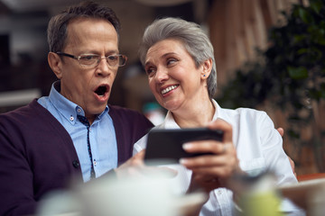 Shocked mature man look at smth in mobile phone