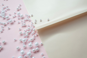 a sheet of paper with a scattered pearl on pink background. Abstract soft pastel colors backdrop.